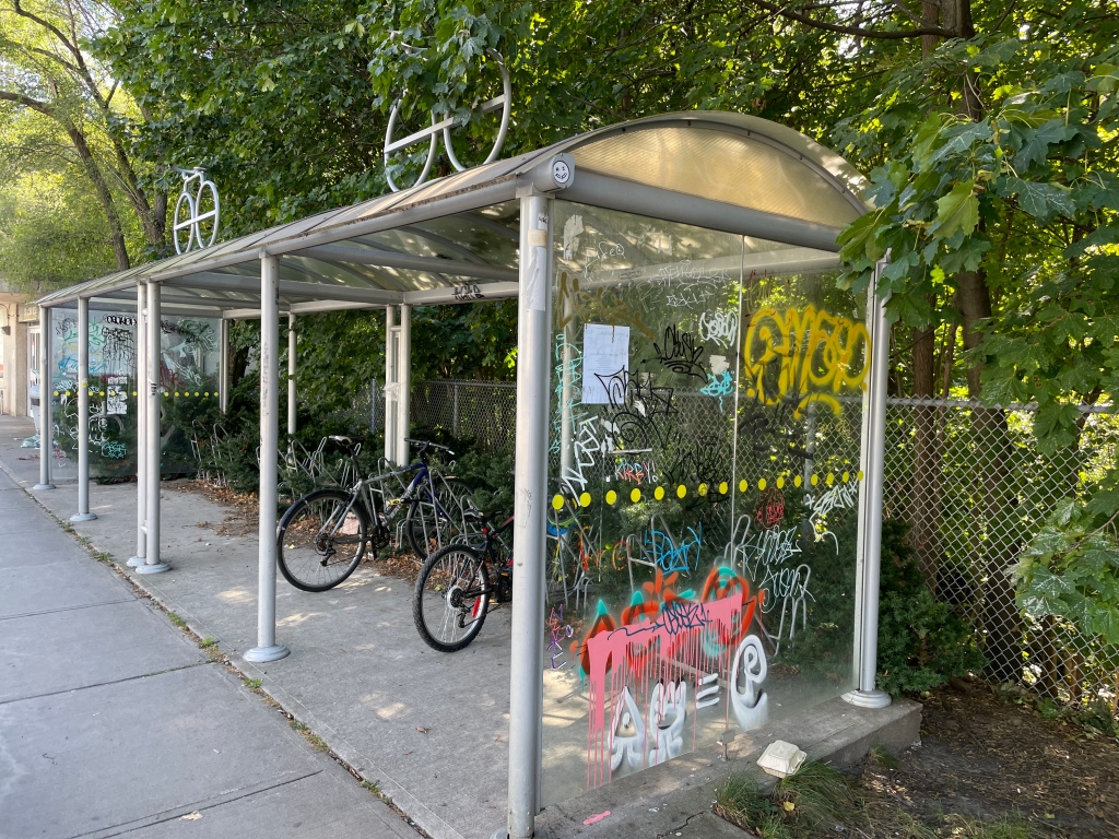 Graffiti-strewn bike rack (about 20 feet wide), with bicycle sculptures on roof